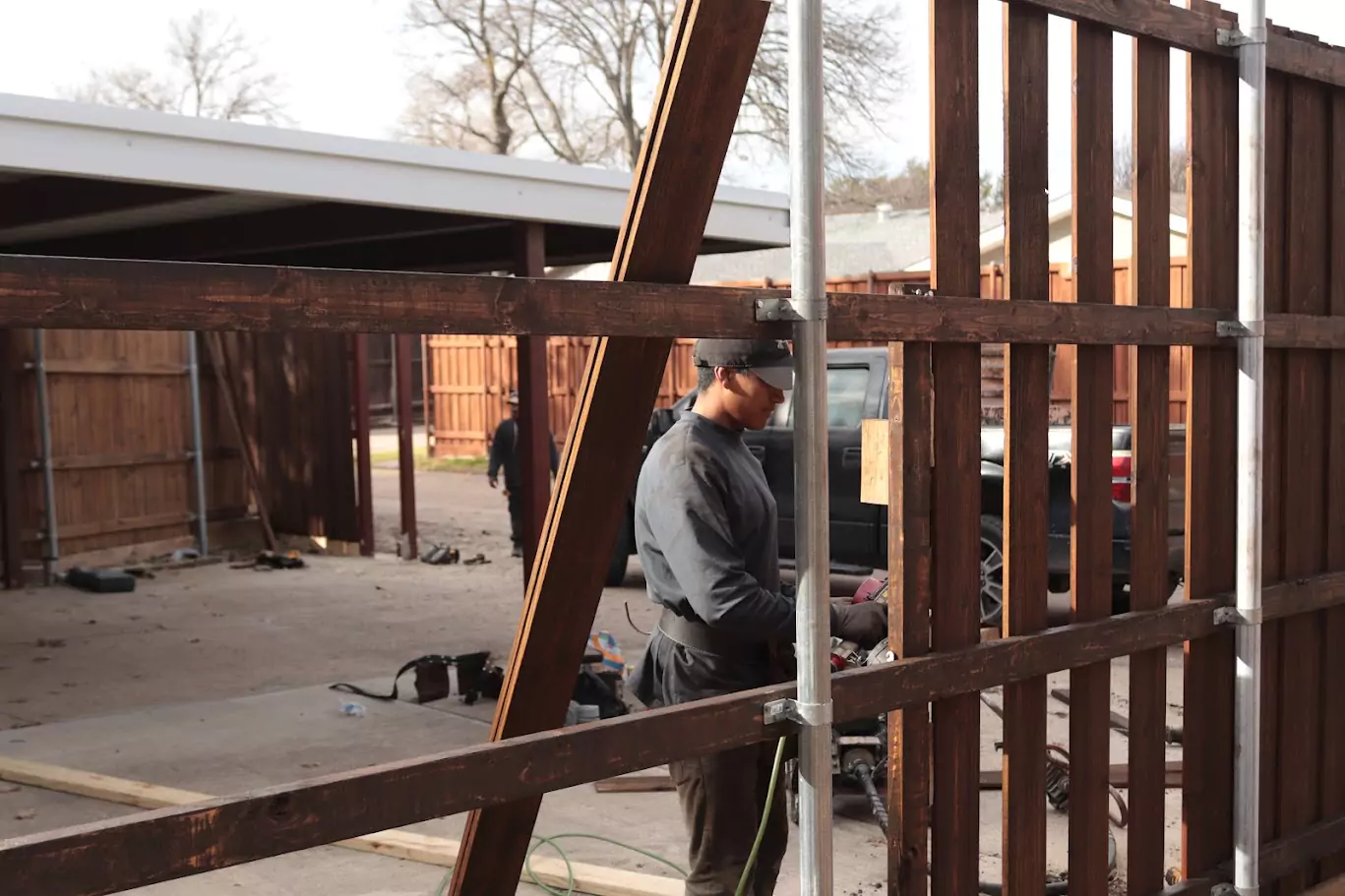 Contractor welding a metal fence frame for a custom wood and metal fence installation in Southlake, TX.