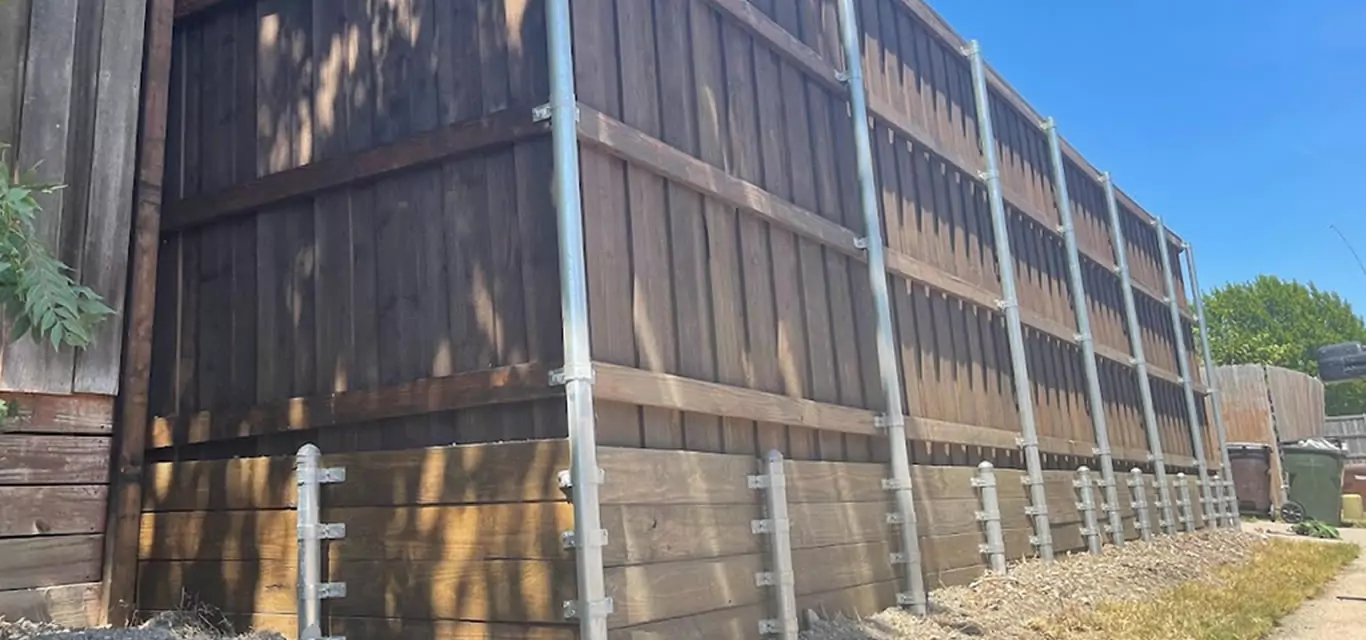 Treated pine retaining wall with support posts under a cedar fence