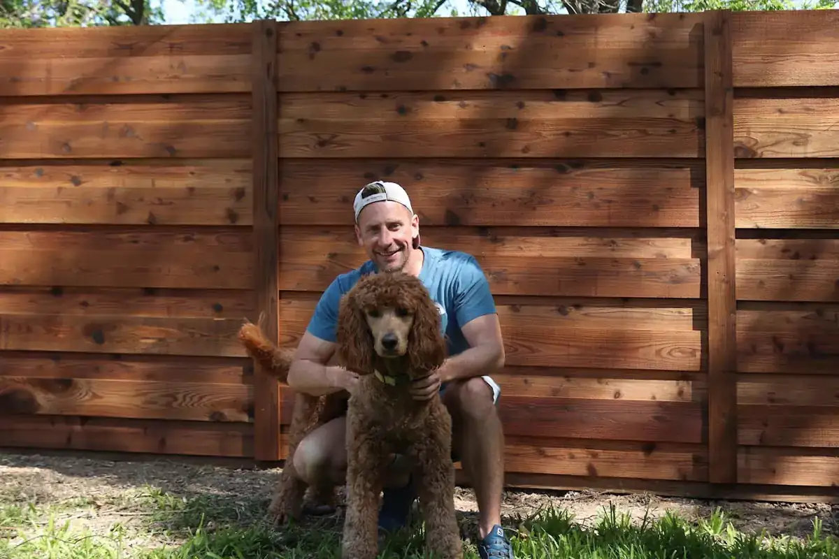 Homeowner and his dog in front of a new horizontal cedar fence